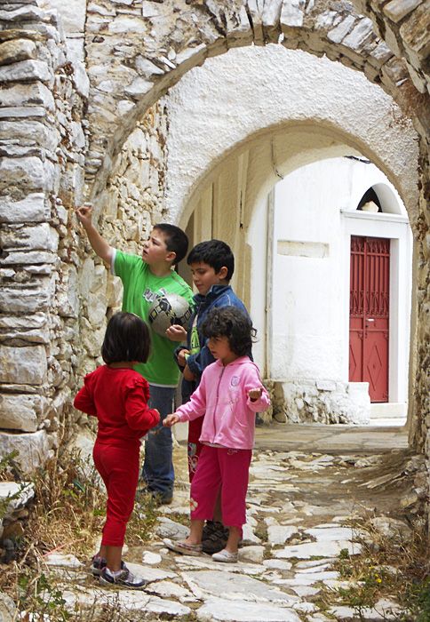 These children are collecting something from the cracks in the wall, but I don\'t know what. Seeds, insects, plants?