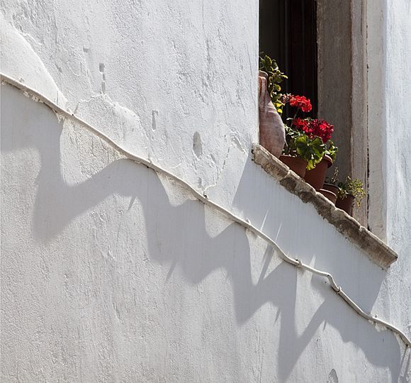 Geraniums in window, with electrical conduit - Naxos town.
