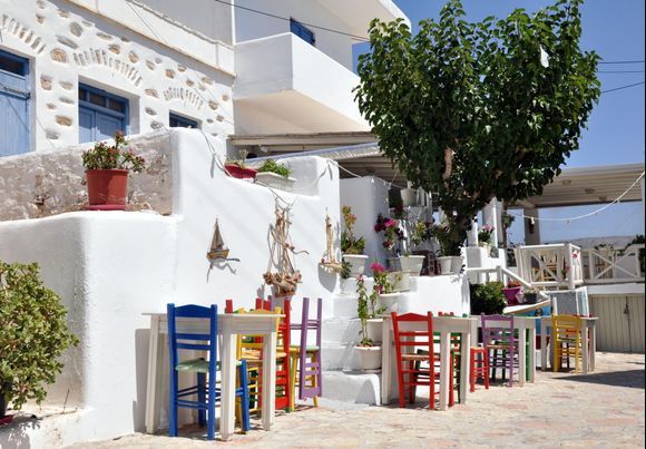 Picturesque street of Koufonisia with colored chairs. 