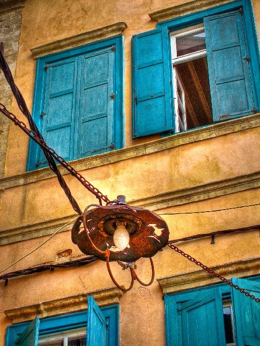 A street lamp hangs across an alleyway in the old town of central Chania, Crete. These old lamps feature a decorative dolphin motif.