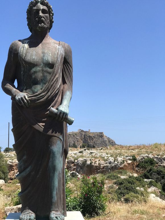 The Statue of Cleobulus, standing proudly in front of The Acropolis of Lindos.