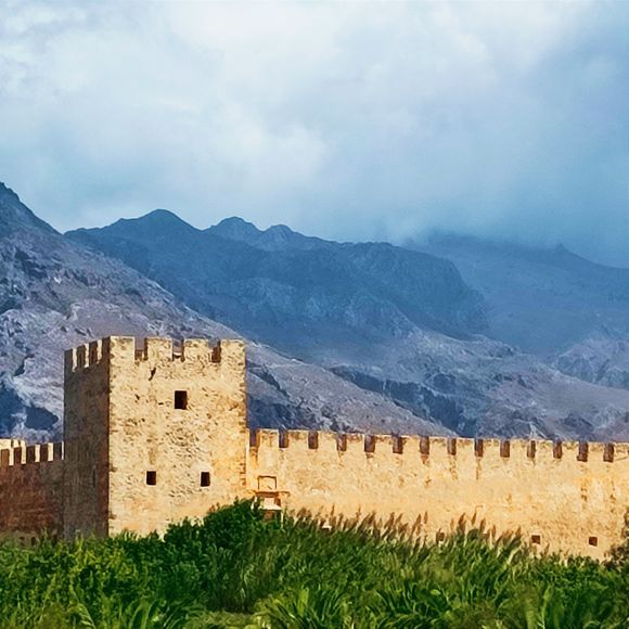 Frangokastello 

The castle was built by the Venetians in 1371–1374 as a garrison to impose order on the rebellious Sfakia region, to deter pirates, and to protect Venetian nobles and their properties. The Venetians named it the Castle of St. Nikitas after the nearby church. The locals, however, who never saw it in a positive light, contemptuously dubbed it Frangokastello, meaning the Castle of the Franks (i.e. Catholic foreigners), Castelfranco or Franco Castello.[1] The name eventually stuck and was adopted by the Venetians as well. According to local lore, when soldiers and builders arrived on the fertile plain to begin construction of the castle, the local Sfakians, led by six Patsos brothers from the nearby settlement of Patsianos, would destroy every night what the Venetians built during the day. Eventually, the Venetians were forced to bring in additional troops and the Patsos brothers were betrayed, arrested and hanged.
Source: Wikipedia 