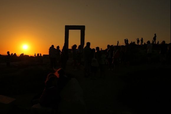 Naxos portara at sunset with people watching