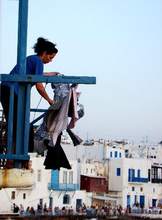 A lady doing her laundry at her balcony over little venice in Mykonos.
