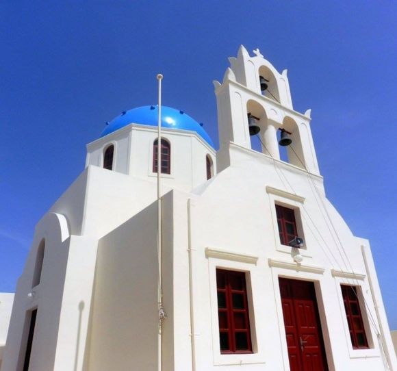 Blue dome church in Santorini  against a beautiful blue sky