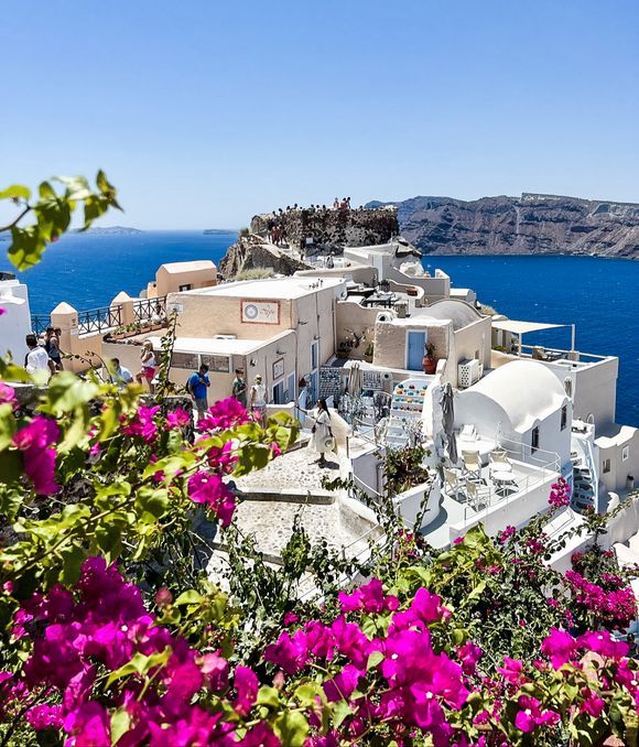 Views of Oia castle in the distance peeking through flowers 