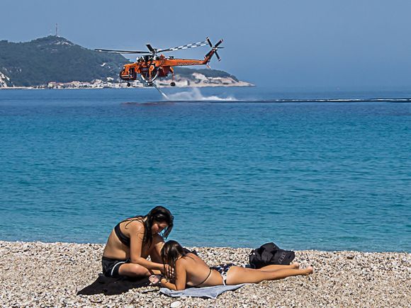 Fire fighting copter and oblivious girls on the beach.