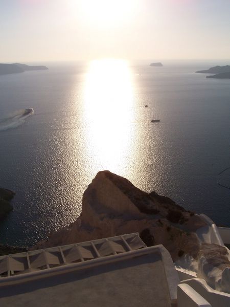 Bodacious bolder silhouetted by sunlight shining the silvery sea.