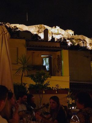 People at a cafe at night at the foot of the Acropolis