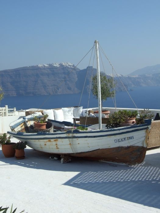 Walking between Fira and Firostefani - deserted fishing boat high up on the roof tops of a restaurant.
