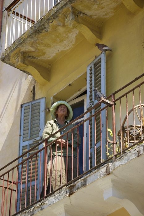 Old lady feeding the pigeons on her balcony in Corfu Town