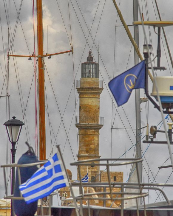 Chania's Venetian lighthouse seen through sailboat masts and rigging.