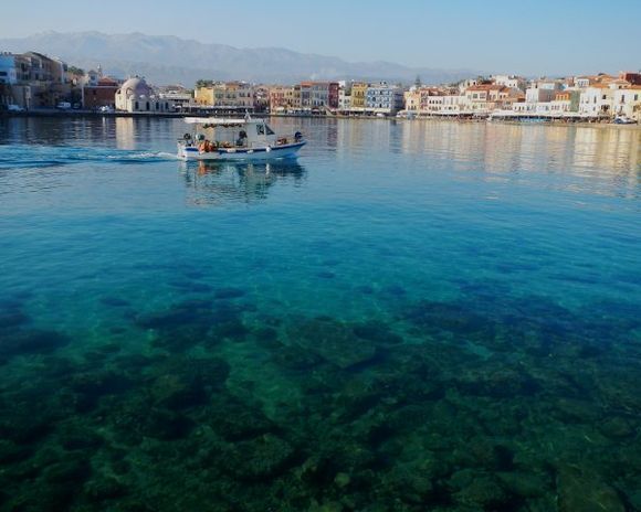 A kaiki heads out for a day of fishing across the crystal clear water of the Chania harbor.