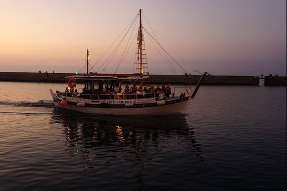 A private sunset cruise boat returns to Chania's Old Harbor.