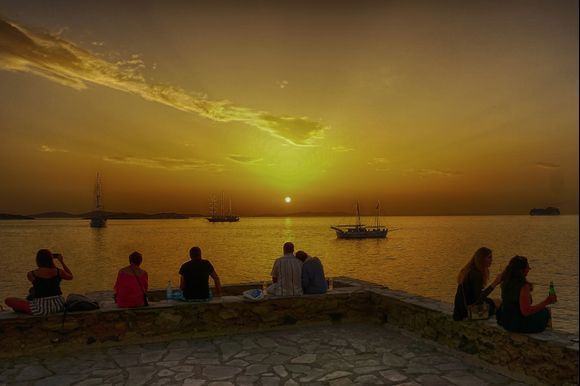 Visitors take in a Mykonos sunset from a relaxing vantage point beside the historic Panagia Paraportiani Church. https://www.greeka.com/cyclades/mykonos/sightseeing/panagia-paraportiani/
