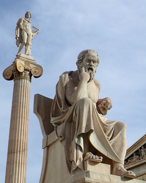 Statue of Socrates outside the Academy of Athens with statue of Apollo on the left.