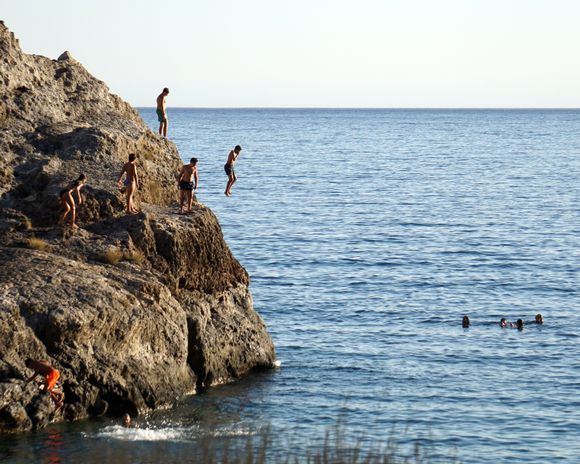 Young people enjoying the thrill of jumping from the rocks at Psilos Bolakas (Tall Rock) Beach near the town of Paleochora.