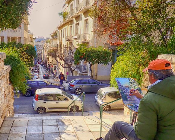 With the Acropolis in the distance, an artist works on an Athens street scene from Kolonaki.