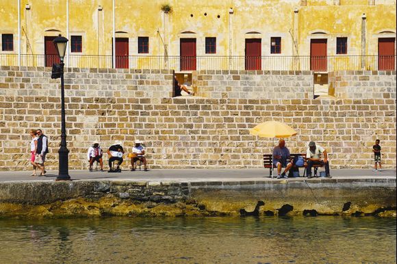 A street scene in Chania's old harbor. Catch a fish, play a tune, sit and rest, or just keep walking.