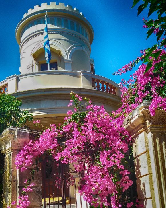 Chania Despotiko (Bishop's residence) with bougainvillea covering the entrance gate.
The Episcopal Residence (Despotiko) was built in the early 20th century as a residence/office by Engineer M. Savakis. The building, in the style of a villa, is constructed on three levels. Clearly influenced by foreign architecture, it gives the impression of a small castle. In 1917, it was sold to the monasterial commission and has since been the residence of the Bishop of Kythonia and Apokorona.