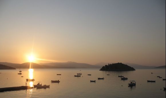 Lone boy fishing from the sea in Tolo, Greece at sunrise.