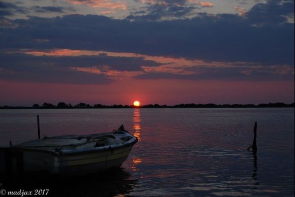 Sunset over tiny fishing boat, moored just off Lefkada Island.