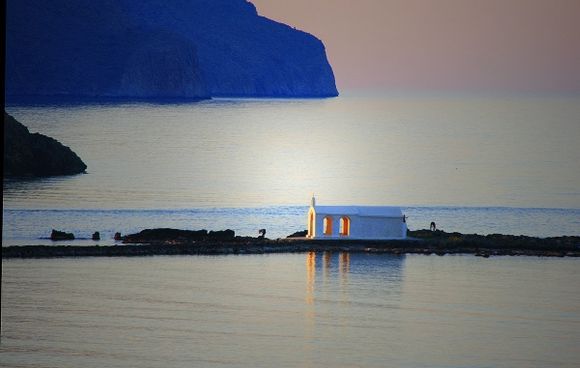 the last light of the day falls on the chapel on the courseway in the sea at Georgioupolis, Crete
