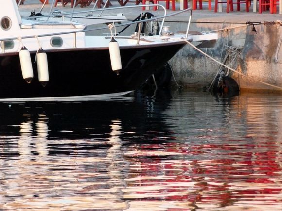 Black boat, red chairs and reflections