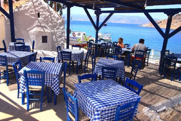 Pretty taverna with church and turquoise sea, Mandraki