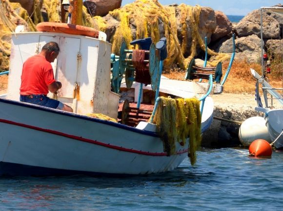 Small harbour with fisherman mending nets. Aegina
