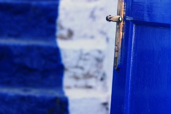 Blue door opening on blue and white flight of stairs. Hydra town