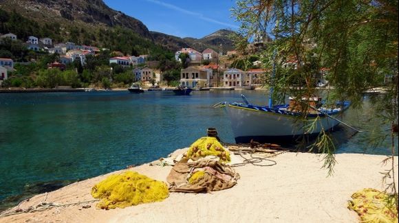 Waterfront with fishing boat and yellow nets. Kastellorizo island, Dodecanese