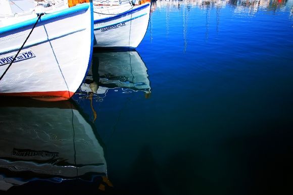 Blue Mediterranean and reflection of fishing boats, Naoussa harbour