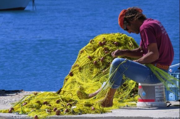 Fisherman mending yellow nets