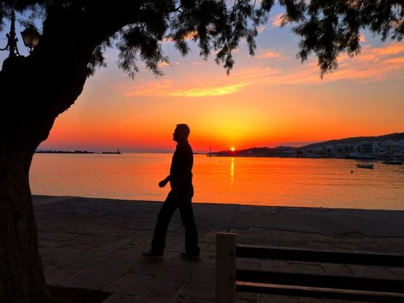 Passerby at sunset on Tinos town promenade
