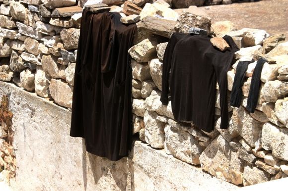 Black clothes drying on a stonewall in Koronos village