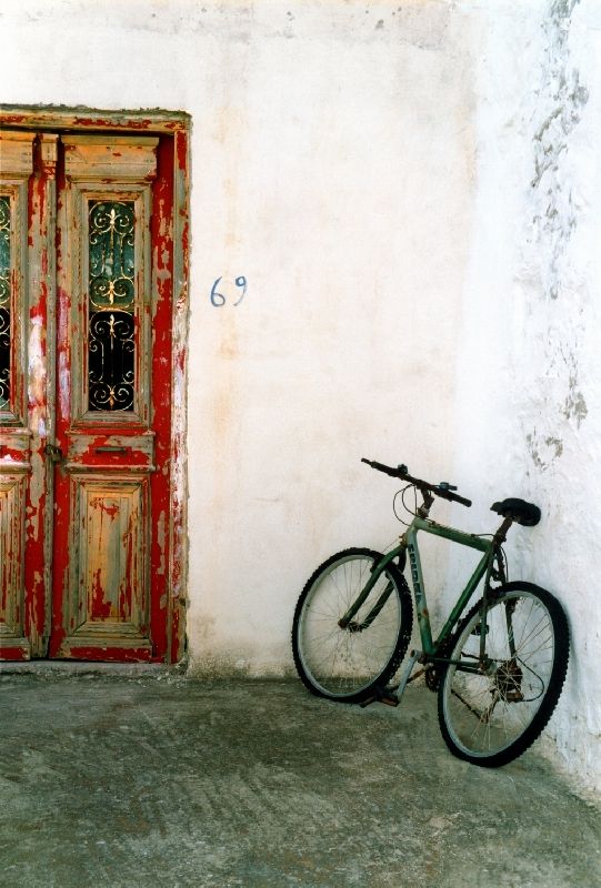 Facade with decayed door and old bicycle in Chora, Kythnos island