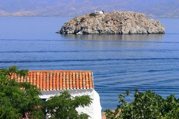 Seascape wit rocky islet and red tiled pretty house in Vlyhos