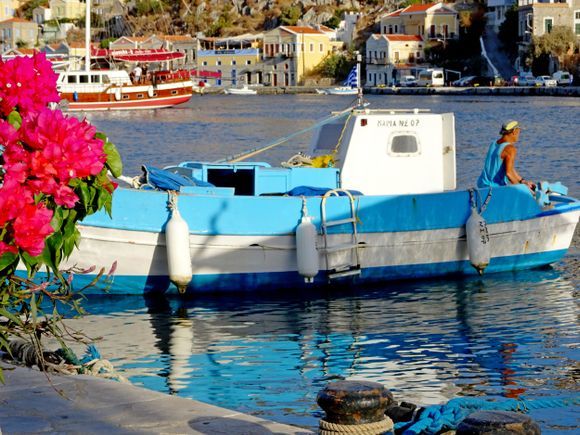 Wooden fishing boat with pink bougainvillea. Gialos harbour, Simi island, Dodecanese