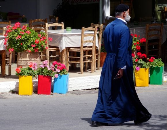 Pope walking past a colorful taverna, Filoti, Naxos island