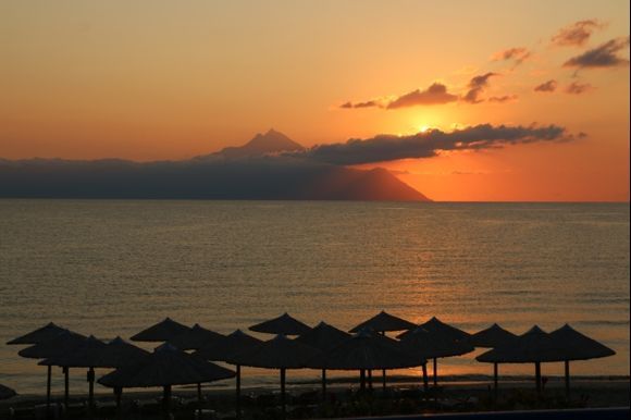This photo was taken on the beach in front of the hotel Agni in Sarti. The sun, rising from behind the mount of Athos sprinkles charm and beauty while passing through the ribbon of clouds...