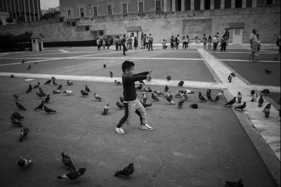 A young boy poses among a flock of pigeons outside of the Parliament building in Athens, Greece.