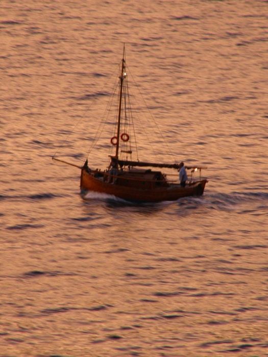 Little sailing boat at sun set