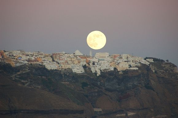 a gigantic moon rising over fairytale Fira.