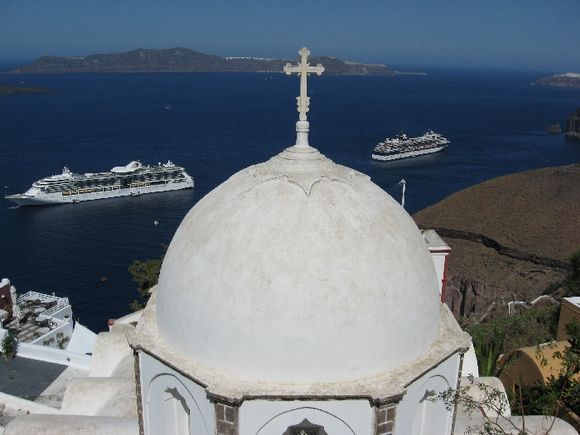 Santorini, the white dome of Catholic church in Fira, in the background the island of Thirasia