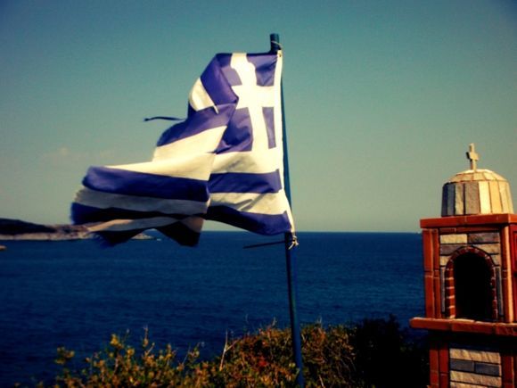 Halkidiki (Sithonia), the greek flag and the small church in the island in front of Kalamitsi beach