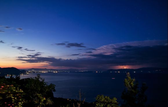 Blue hour sunset looking to Corfu town from Chlomos church with stars above and a complimentary storm over the mainland.