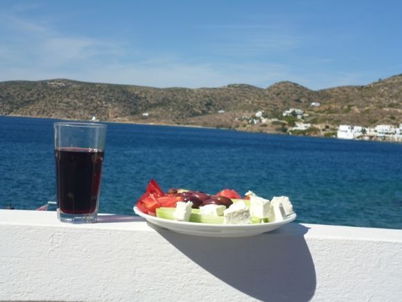 A glass of wine, Feta cheese, tomatoes, cucumbers, Greek olives and a view  to take in as you enjoy lunch!
