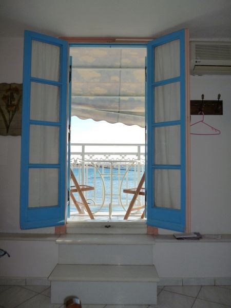St. George Beach studio with a view from my bed through double doors, a balcony and the blue Aegean in the background.