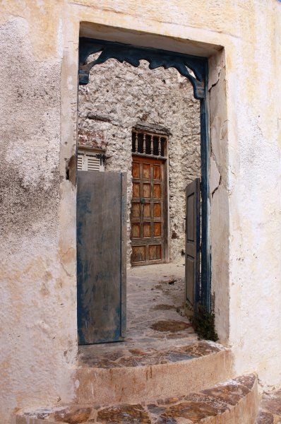 An open gate reveals an old door in the village of Emporio.